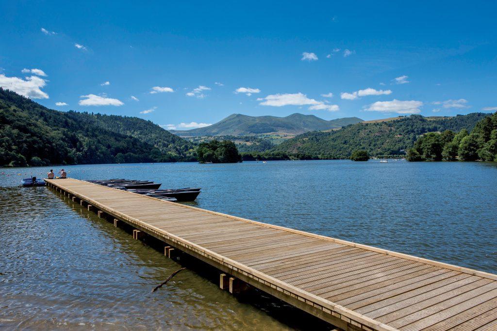 Vue sur le lac Chambon possédant une plage accessible. On voit un ponton au premier plan.